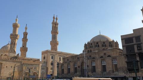       Panoramic view of Al-Azhar Mosque complex with multiple minarets under a clear sky.
  
