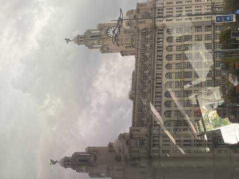      Royal Liver Building with clock tower seen through bus window reflections on a cloudy day.
  