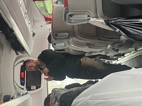       Tour guide standing in coach aisle speaking into microphone to passengers.
  