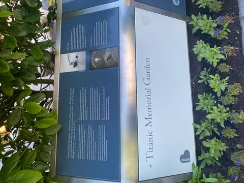       Interpretive panel for Titanic Memorial Garden surrounded by leafy plants.
  