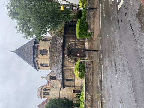       Historic round church built of stone under light rain in Cambridge.
  