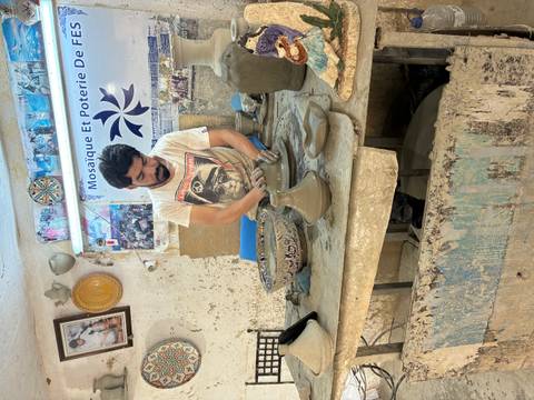       Artisan shaping clay on a potter’s wheel in a traditional Moroccan ceramics workshop.
  
