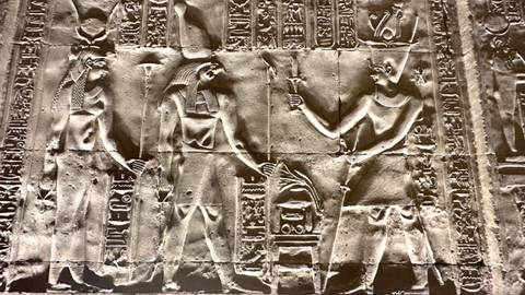       Detailed ancient Egyptian wall relief depicting deities and hieroglyphs carved in stone.
  