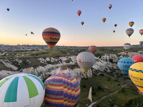       Dozens of colourful hot-air balloons drift over Cappadocia’s otherworldly rock valleys at sunrise.
  
