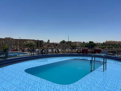       A close shot of an empty blue swimming pool aboard a Nile cruise ship under clear skies.
  