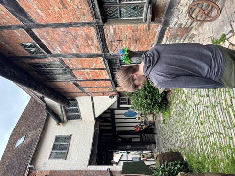       Young traveler standing in a cobblestone courtyard beside a half-timbered medieval building.
  