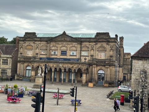       York Art Gallery’s sandstone façade with arched windows and banners under a dull sky.
  