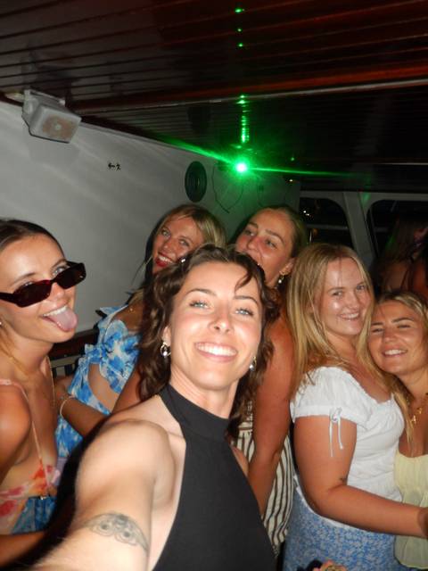       Close-up party selfie of smiling friends dancing in dim cabin lighting.
  