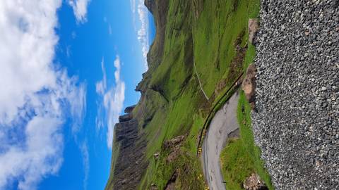       Dramatic viewpoint over the green cliffs and winding single-track road of the Quiraing, Isle of Skye.
  