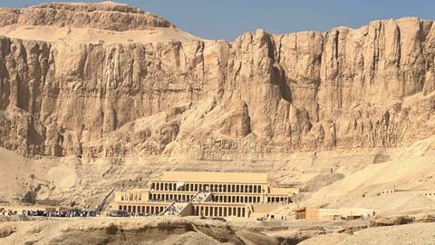       Mortuary Temple of Hatshepsut backed by dramatic desert cliffs with visitors gathered below
  
