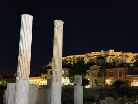       Night view of classical columns with the Acropolis hill lit in the background
  
