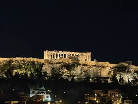       The Parthenon atop the Acropolis illuminated against a dark night sky
  