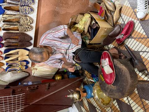       Skilled cobbler hand-stitching leather slippers in a traditional Moroccan workshop.
  