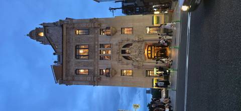       Elegant early 20th-century building illuminated at dusk on a Kyoto street bustling with pedestrians.
  