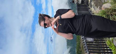       Smiling visitor forms a heart shape with hands against a cloud-capped Mount Fuji backdrop
  