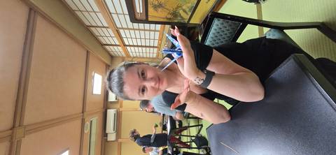       Woman displaying an origami crane in a traditional tatami room workshop
  