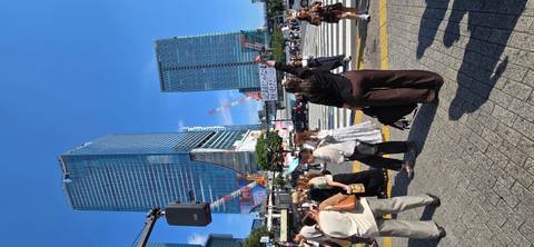       Crowded crosswalk beneath soaring skyscrapers and construction cranes on a sunny day
  