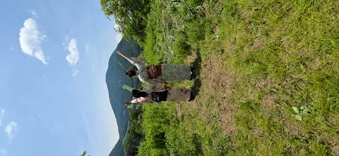       Two women in floral kimono raise their arms toward verdant mountain slopes
  
