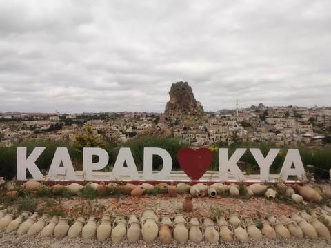       Scenic vista of Cappadocia town with large rock outcrop behind heart-shaped sign
  