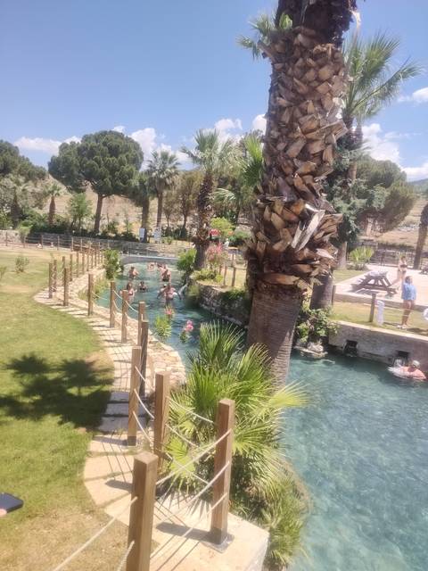       Thermal canal lined with palms and swimmers enjoying warm spring water
  