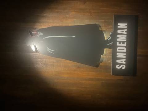       Back-lit wall sign of the Sandeman caped figure logo inside a dim tasting room
  