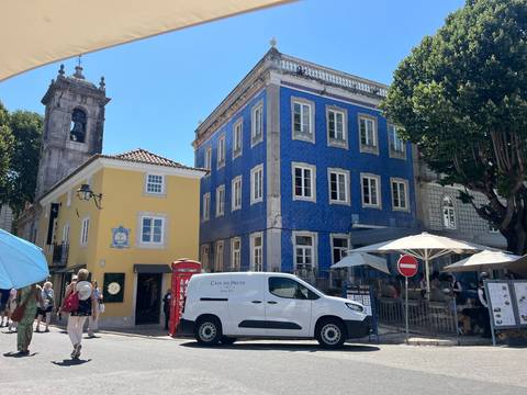      Sunny plaza featuring a striking blue-tiled mansion, yellow house and outdoor cafés
  