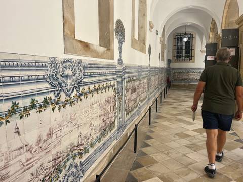       Long corridor lined with intricate blue-and-white azulejo panels inside a monastery
  