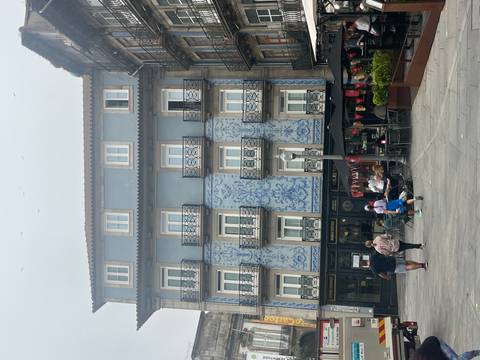      Blue azulejo-clad residential building overlooking a small square with families
  