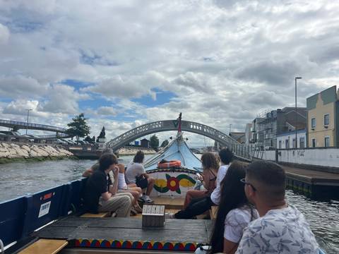       Group enjoying a colorful moliceiro boat ride under a low bridge on Aveiro canal
  
