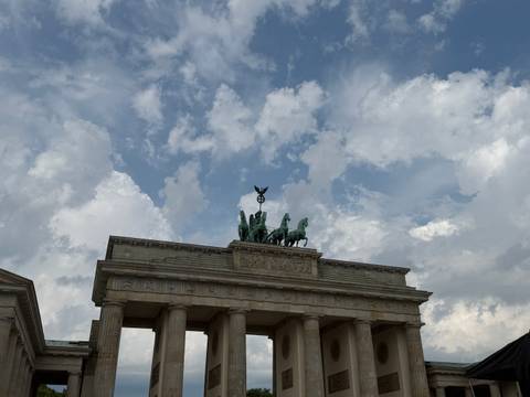       Upward view of the Brandenburg Gate’s quadriga set against a partly cloudy blue sky
  