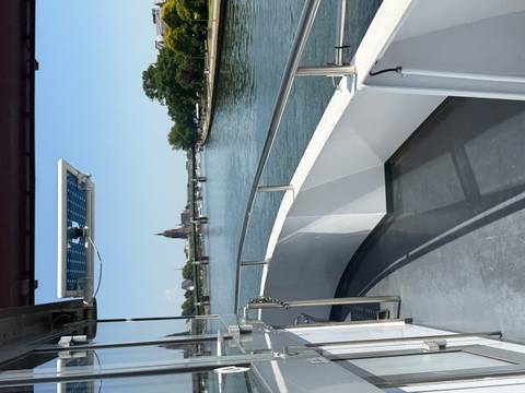       View from a riverboat deck looking toward Frankfurt’s skyline with a cathedral spire and bridges over the Main
  