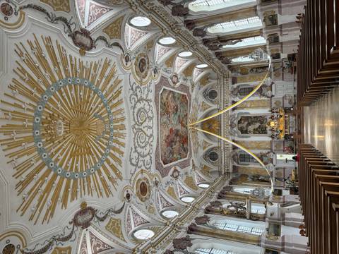       Ornate Baroque church interior with a gilded sunburst ceiling and richly decorated altar
  
