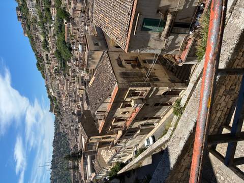       Panoramic view across the steep stone lanes and terracotta roofs of Modica’s old town
  