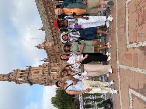       Small tour group posing in front of the ornate towers and arches of Plaza de España.
  