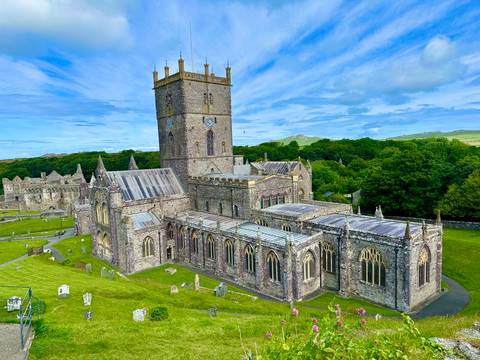       A stunning elevated view of St Davids Cathedral and surrounding stone structures bathed in soft morning light.
  