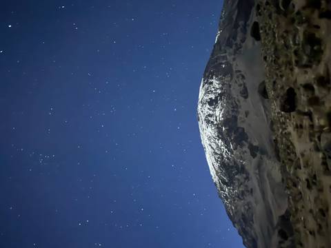       Snow-capped mountain summit beneath a clear star-filled night sky.
  