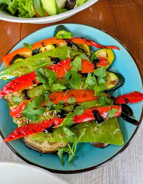       Colorful grilled peppers and zucchini drizzled with balsamic glaze are garnished with fresh parsley.
  