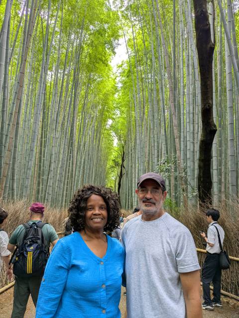       Smiling tourists pose among towering bamboo stalks in a crowded forest path
  
