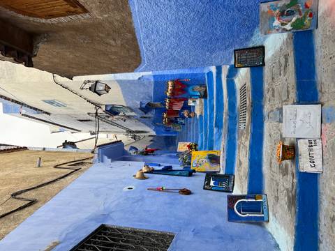       Narrow blue-painted stairway in Chefchaouen lined with local artwork and colorful crafts
  