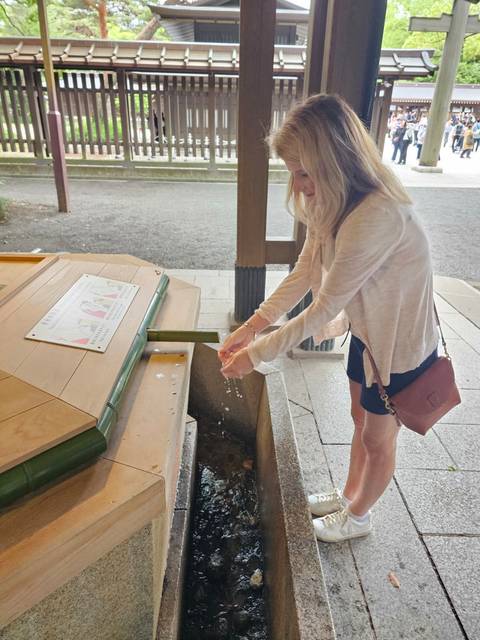       Traveller ritually rinses hands at a bamboo water spout inside a Japanese shrine.
  
