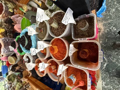       Buckets of bright red and brown spices for sale at a bustling Bhutanese market stall
  