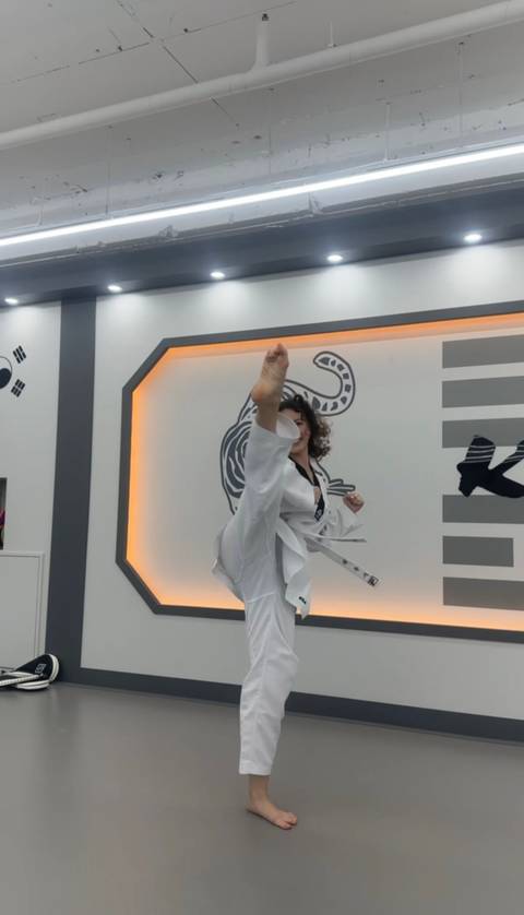      Martial artist performs a high kick in a modern dojang with illuminated wall design.
  