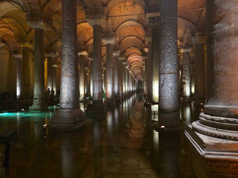       Atmospheric interior of Basilica Cistern with illuminated columns reflected in shallow water.
  