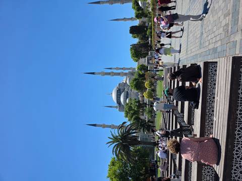       Visitors relaxing on benches facing the Blue Mosque across landscaped square.
  
