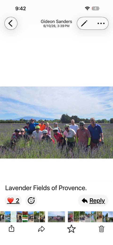       Cycling group posing in a blooming lavender field with mountains in the distance.
  
