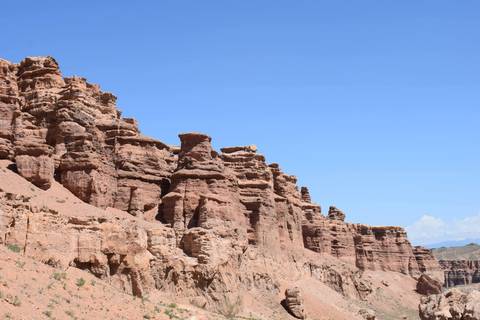       Red sandstone formations of Charyn Canyon towering against bright blue Kazakh sky
  