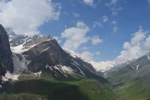       Snow-capped peaks and green valley of Fann Mountains beneath scattered clouds
  