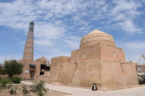       Brick mausoleum and minaret of Itchan Kala in Khiva under partly cloudy sky
  