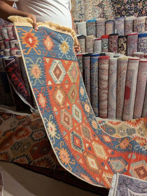       Display of colorful Turkish carpets and rolled rugs inside a shop
  
