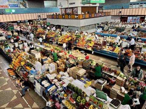       Bustling indoor produce market packed with colourful fruit and shoppers
  